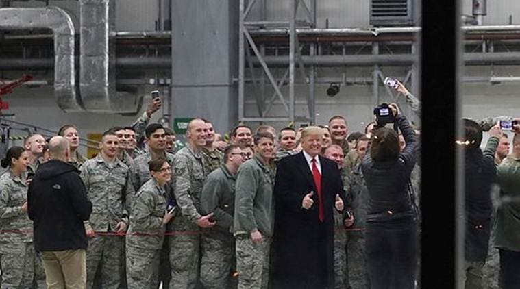 US President Donald Trump is seen through glass as he takes a photo with US troops at Ramstein Air Force Base in Germany on Thursday. (Reuters)