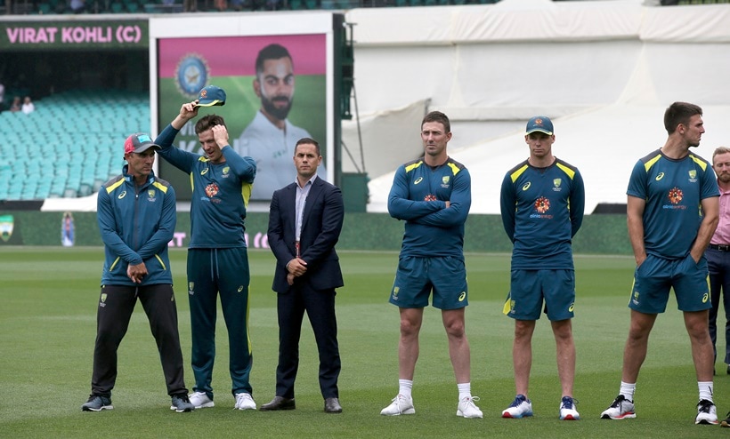 Australian team members stand by as India's Virat Kohli accepts the winners trophy after play was called off on day 5 of their cricket test match in Sydney
