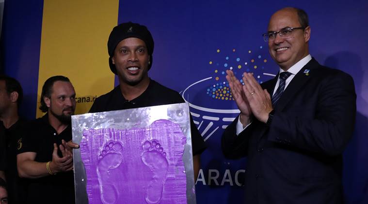 Brazil's former soccer player Ronaldinho shows his footprints, next to the Rio de Janeiro Governor Wilson Witzel (R), to be included in the Maracana's hall of fame, in Rio de Janeiro, Brazil