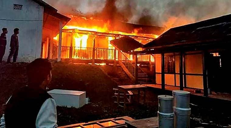 A building set on fire after a mob went on a rampage during a protest against the move to grant permanent resident certificates to six communities living in the state on Sunday. (PTI)