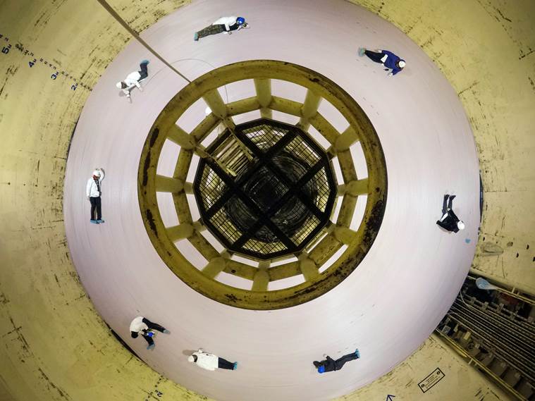 Workers sit on a giant spool of fiber-optic cable