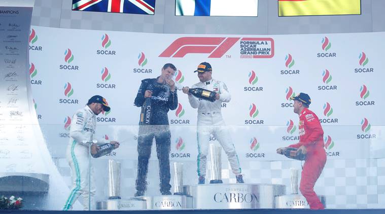 Mercedes' Valtteri Bottas celebrates winning the race with Mercedes mechanic Stuart Green, second placed Lewis Hamilton and third placed Ferrari's Sebastian Vettel on the podium