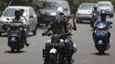 A man rides a motorcycle with his face covered in cloth to protect from heat on a hot summer afternoon in Hyderabad, Wednesday. (AP Photo)