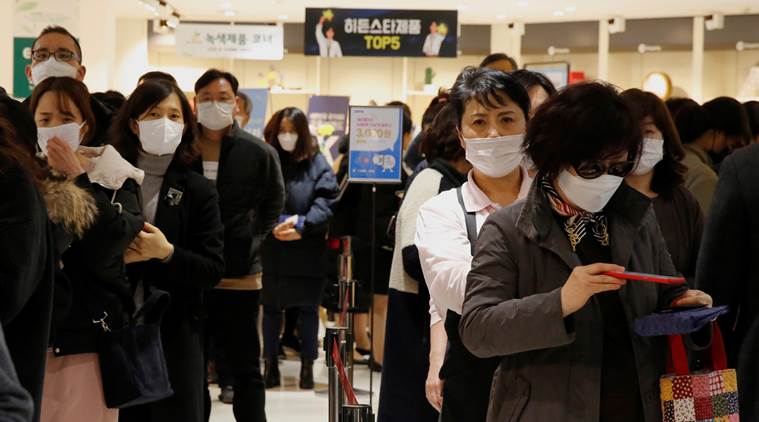 People wearing masks to prevent contracting the coronavirus wait in line to buy masks at a department store in Seoul