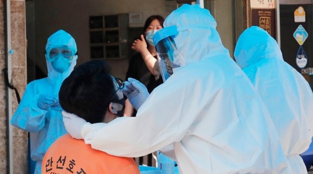 A health official wearing protective gear takes samples from a man during the COVID-19 testing at a makeshift clinic in Seoul, South Korea, (AP Photo/Ahn Young-joon)