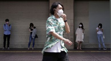 People wearing masks against the spread of the new coronavirus keep social distancing while hanging out near Shibuya pedestrian crossing in Tokyo Friday, July 31, 2020. (AP Photo/Eugene Hoshiko)
