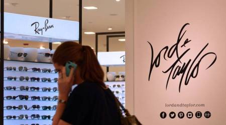 A shopper talks on her cell phone in front of signage and a display of Ray Ban sunglasses at the newly opened Hudson's Bay Co. Lord  & Taylor LLC department store in Boca Raton, Florida, U.S., on Thursday, Oct. 10, 2013. Retail sales figures, which were scheduled for Oct. 11 by the U.S. Census Bureau, will not be released due to the partial government shutdown. Photographer: Mark Elias/Bloomberg