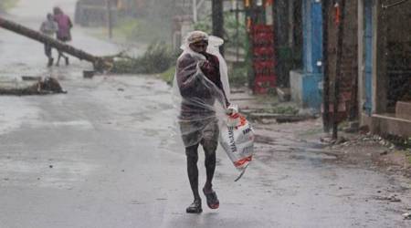 A man covers himself with a plastic sheet and walks in the rain at Bhadrak district in Odisha. (AP)