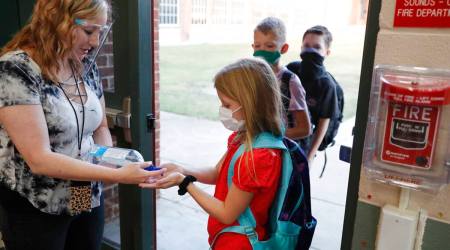 In this file photo, wearing masks to prevent the spread of COVID19, elementary school students use hand sanitizer before entering school for classes in Godley, Texas (AP)
