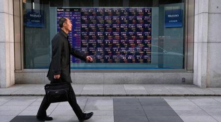 A pedestrian walks past an electronic stock board outside a securities firm outside a securities firm in Tokyo, Japan, on Friday, Jan. 4, 2019. (Photographer: Takaaki Iwabu/Bloomberg)