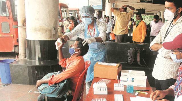 A healthcare worker collects a swab sample for an antigen test at Khopat bus stand in Thane on Thursday.  (Express photo by Deepak Joshi)