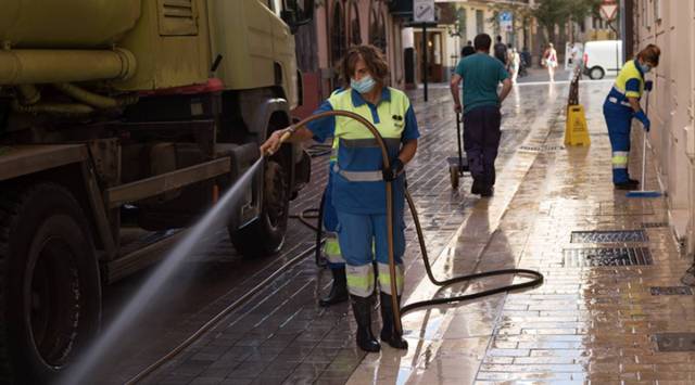 A street cleaner hoses down a sidewalk in Malaga, Spain, on Saturday, August 29, 2020. (Samuel Aranda/The New York Times)
