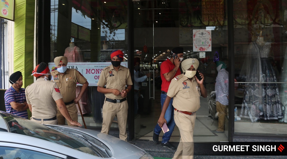 Police outside a shop that opened, defying Punjab government guidelines allowing only 50% shops to open, in Ludhiana on Monday. HOwever, the condition has now been removed. (Express Photo: Gurmeet Singh)