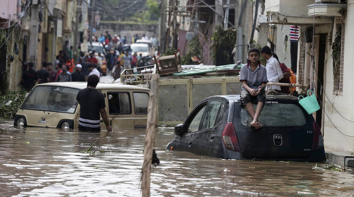 A boy sits on a car at a flooded street after heavy rainfall at Baba Nagar in Hyderabad (AP)