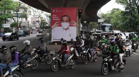 Motorcyclists drive past a poster of Indonesian President Joko Widodo urging people to wear masks in Bandung, West Java, Indonesia (Bloomberg)