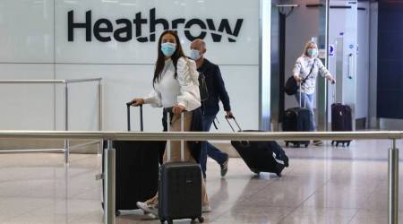 Passengers, wearing protective face masks, walk through the international arrivals hall after arriving at Terminal 2 at London Heathrow Airport in London, U.K