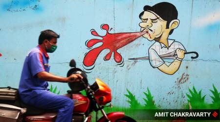 A man drives past a wall painting spreading the message of not spitting in public places. (Express Photo by Amit Chakravarty/File)