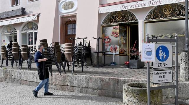 An innkeeper is moving his chairs outside in the pedestrian zone of the city centre of Berchtesgaden, Germany, Tuesday, Oct.20, 2020. From 2 pm on the exit restrictions in the district of Berchtesgadener Land come into force. (Peter Kneffel/dpa via AP)