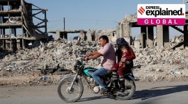 FILE PHOTO: Motorists ride a motorcycle past ruins of buildings destroyed during fightings with the Islamic State militants in Kobani no alt set