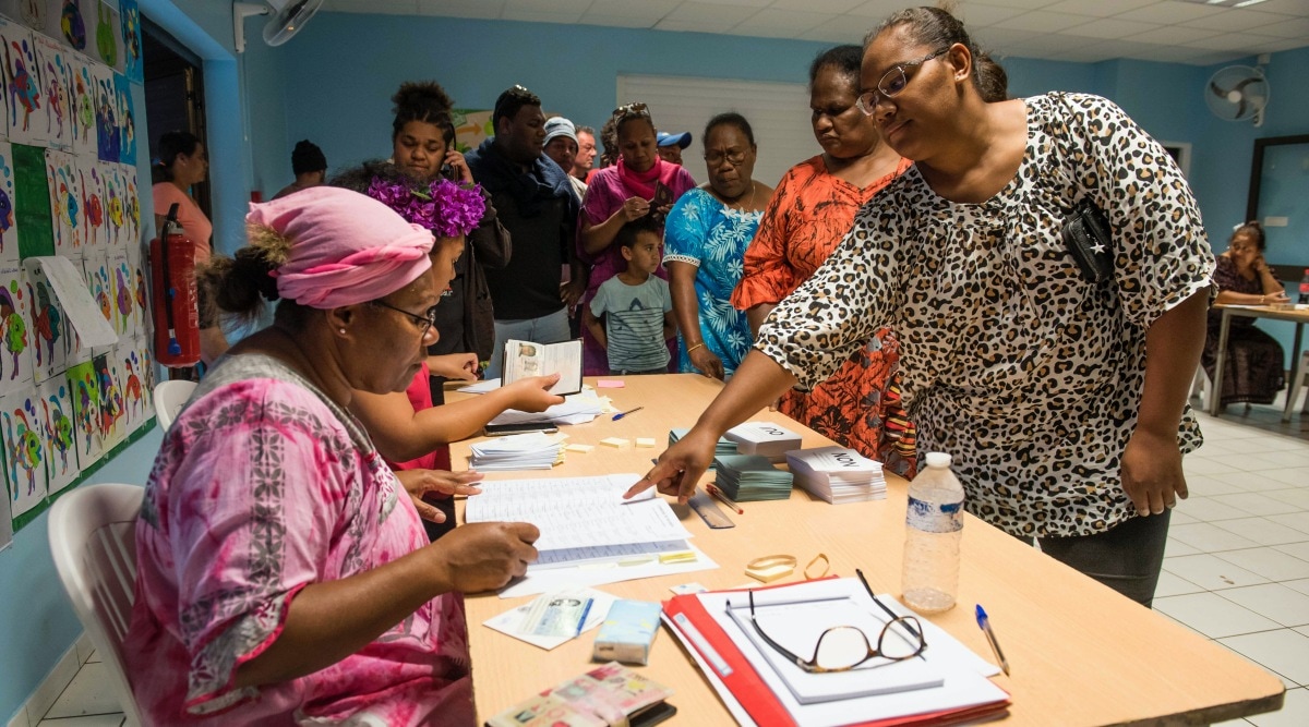 A woman points to a voting notebook before voting in Noumea, New Caledonia, Sunday, Oct.4, 2020. Voters in New Caledonia, a French archipelago in the South Pacific, were deciding Sunday whether they want independence from France in a referendum that marks a milestone in a three-decade decolonization effort. If voters choose independence, a transition period will immediately open so that the archipelago can get ready for its future status. Otherwise, New Caledonia will remain a French territory. (AP Photo/Mathurin Derel)