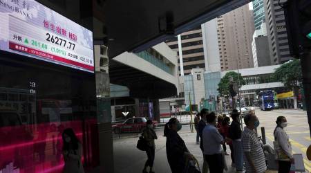 People stand near a bank's electronic board showing the Hong Kong share index at Hong Kong Stock Exchange Tuesday, Nov. 10, 2020. (AP Photo/Vincent Yu)