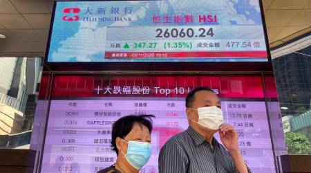 People walk past a bank's electronic board showing the Hong Kong share index at Hong Kong Stock Exchange Monday, Nov. 9, 2020. (AP Photo/Vincent Yu)