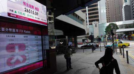 People walk past a bank's electronic board showing the Hong Kong share index at Hong Kong Stock Exchange Tuesday, Nov. 17, 2020. (AP Photo/Vincent Yu)
