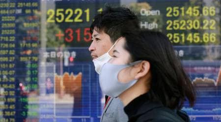 People walk by an electronic stock board of a securities firm in Tokyo, Wednesday, Nov. 11, 2020. (AP Photo/Koji Sasahara)