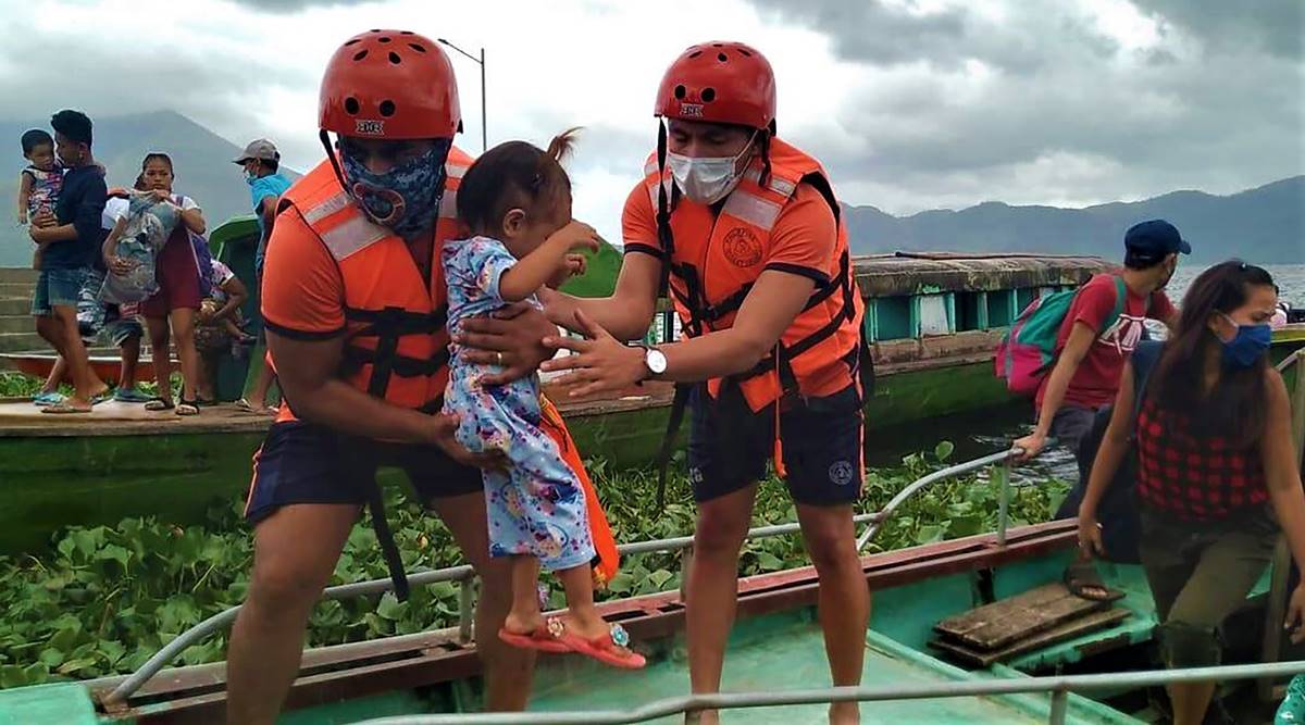In this photo provided by the Philippine Coast Guard, members of the Philippine Coast Guard carry a child as they are evacuated to safer ground in Camarines Sur province, eastern Philippines on Saturday Oct. 31, 2020 as they prepare for typhoon Goni. (Philippine Coast Guard via AP)