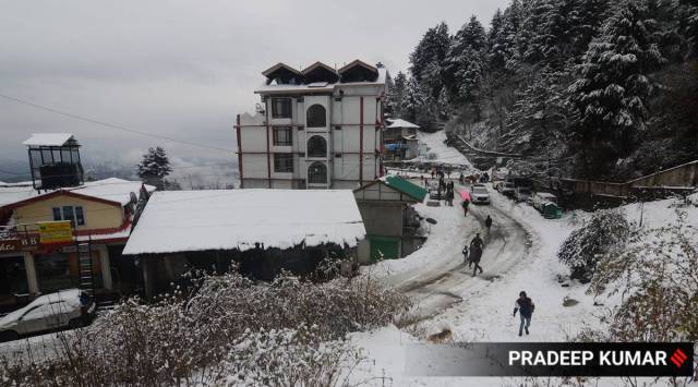 People walk on a snow covered road after fresh snowfall at Kufri near Shimla. (Express Photo by Pradeep Kumar)