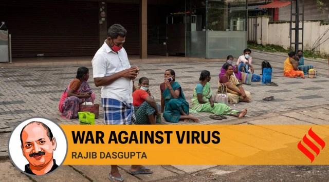 Migrant laborers from Tamil Nadu state wearing face masks as a precaution against the coronavirus wait to be hired for the day, by the side of a road in Kochi (AP)