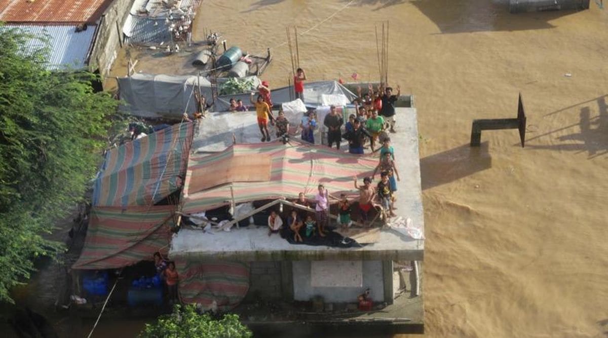 People stand on a roof of a building after Typhoon Vamco resulted in severe flooding, in the Cagayan Valley region in the Philippines, November 14, 2020. Philippine Coast Guard/Handout via REUTERS)