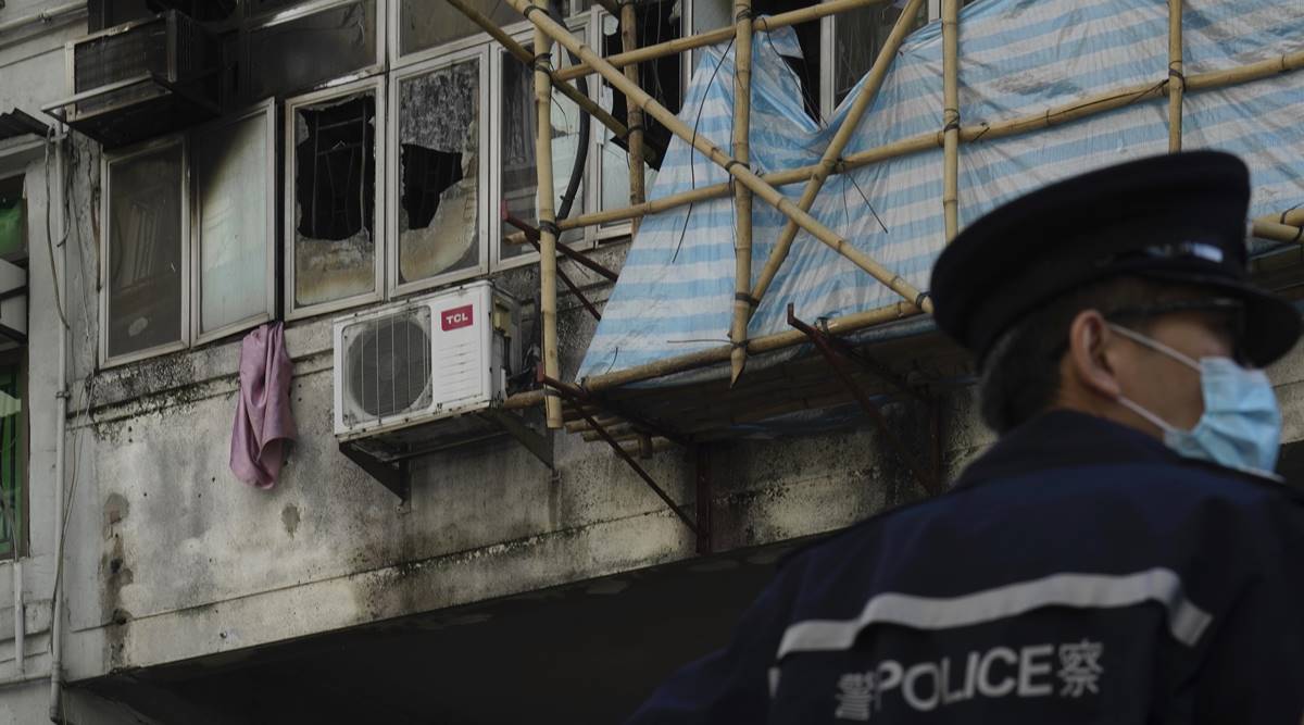A police officer stands guard at a fire site , top left with broken windows, in Hong Kong Monday (AP Photo/Vincent Yu)
