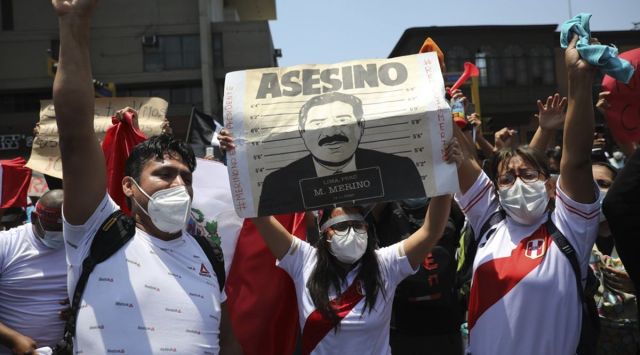 Protesters asking that interim President Manuel Merino step down, hold a sign reading in Spanish "Murderer" shortly before Merino announced his resignation in Lima, Peru, Sunday, Nov. 15, 2020. (AP Photo/Rodrigo Abd)