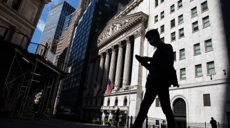 A pedestrian wearing a face mask looks at a smartphone while passing in front of the New York Stock Exchange (NYSE) in New York, US, on Monday, July 20, 2020. (Photographer: Michael Nagle/Bloomberg)