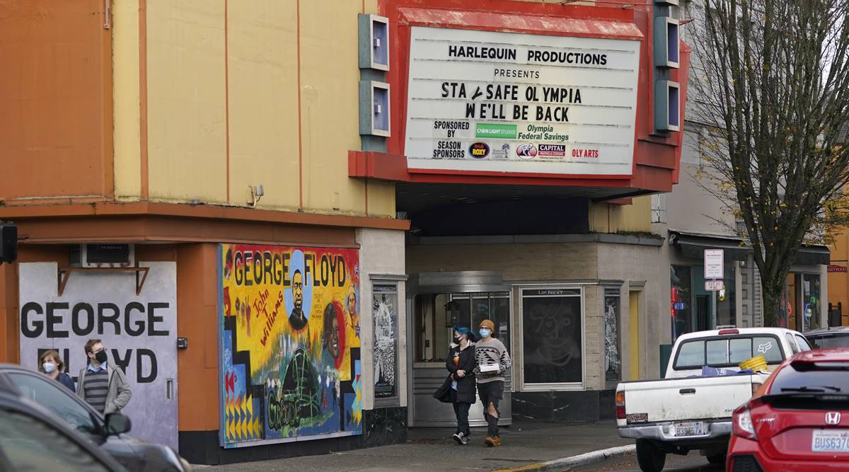People wearing masks walk past the Harlequin Productions theater, Sunday, Nov. 15, 2020, as the marquee reads "Stay Safe Olympia, We'll Be Back," in downtown Olympia, Wash. (AP Photo/Ted S. Warren)