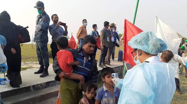 A health worker checks the temperature of Rohingya Muslims arriving at Bhasan Char, or floating island Bangladesh. (AP Photo/Saleh Noman)
