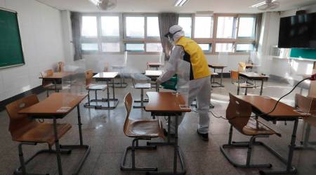 A health official disinfects as a precaution against the coronavirus for the upcoming college entrance exams in a classroom at a high school in Seoul, Dec. 1, 2020. (AP Photo/Ahn Young-joon)