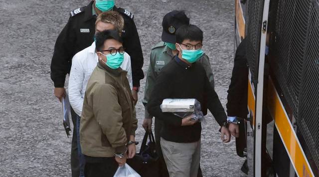 Hong Kong activists Joshua Wong, right, and Ivan Lam, left, are escorted by Correctional Services officers to get on a prison van before appearing in a court, in Hong Kong, Wednesday, Dec. 2, 2020. (AP Photo/Kin Cheung)