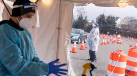 FILE - In this Dec. 9, 2020, file photo, health care workers prepare to test motorists for COVID-19 at a testing site outside McCoy Stadium in Pawtucket, R.I. (AP Photo/David Goldman, File)