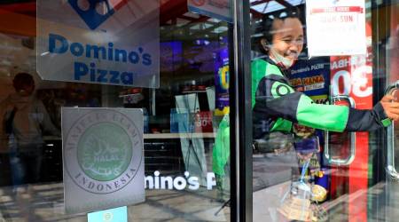 A man leaves as 'halal' logo of Indonesian Ulema Council is displayed on the facade of a restaurant in Jakarta, Indonesia,  (AP Photo/Tatan Syuflana)