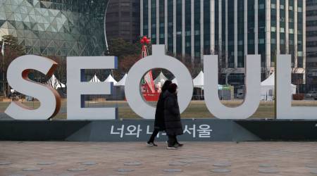 Women wearing face masks as a precaution against the coronavirus walk near the display of South Korea's capital Seoul logo in Seoul, South Korea (AP Photo/Lee Jin-man)