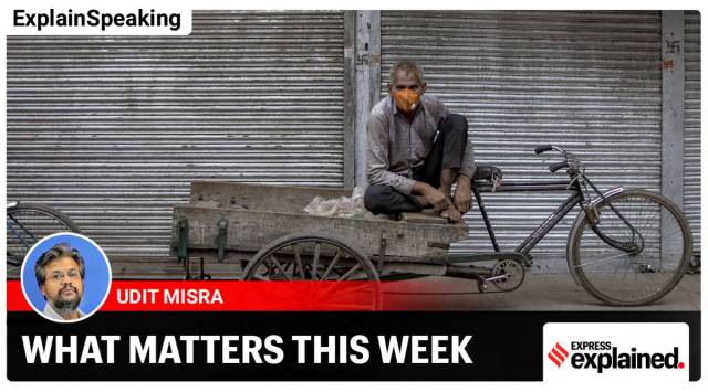 A day laborer wearing a protective mask sits on a tricycle outside a shuttered store in New Delhi (Photographer: Anindito Mukherjee/Bloomberg)