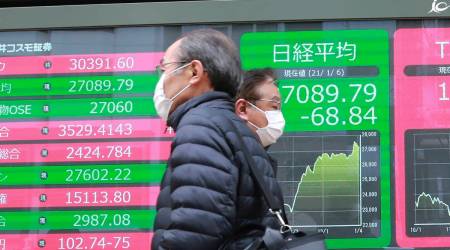 People walk by an electronic stock board of a securities firm in Tokyo, Wednesday, Jan. 6, 2021. (AP Photo/Koji Sasahara)