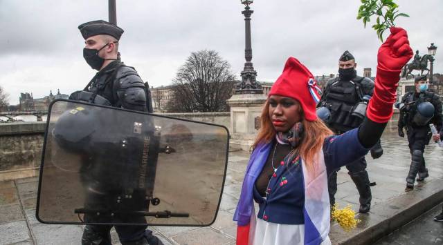 A protester dressed as Marianne, the symbol of the French Republic since the 1789 revolution walks next to riot police officers during a march for freedom in Paris, Saturday, Jan. 23, 2021. (AP Photo/Michel Euler)