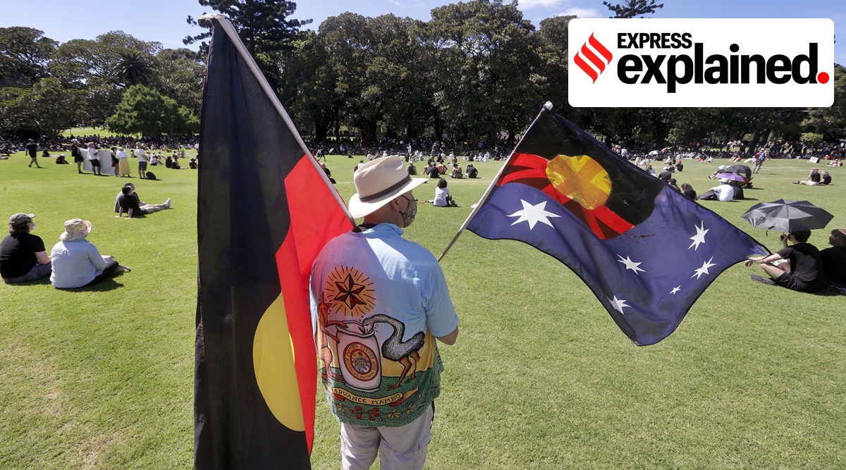 A man holds a modified Australian flag and the Aboriginal flag in a social distanced crowd during an Aboriginal-lead Invasion Day rally on Australia Day in Sydney, Tuesday, Jan. 26, 2021.(AP)