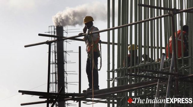 A construction worker speaks on a phone as smoke is seen emitting from a chimney in eastern suburb of Mumbai. (Express Photo by Karma Sonam Bhutia)