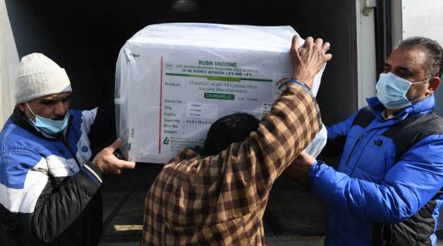 Health workers carry boxes containing Covid-19 vaccines at a hospital cold storage facility in Srinagar. (Express photo by Shuaib Masoodi)