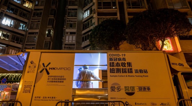 Government workers wearing personal protective equipment (PPE) prepare a mobile testing unit outside a building under lockdown at the Laguna City residential estate in the Kwun Tong neighborhood of Hong Kong, China, on Sunday, Jan. 31, 2021. The government ordered residents in two blocks of a residential estate in the Kwun Tong area of Kowloon Peninsula to stay inside until they have been tested for Covid-19, as the city launches another targeted operation aimed at containing a surge of coronavirus cases.