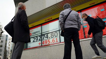 People wearing protective masks to help curb the spread of the coronavirus look at an electronic stock board showing Japan's Nikkei 225 index at a securities firm Monday, Feb. 8, 2021, in Tokyo. (AP Photo/Eugene Hoshiko)